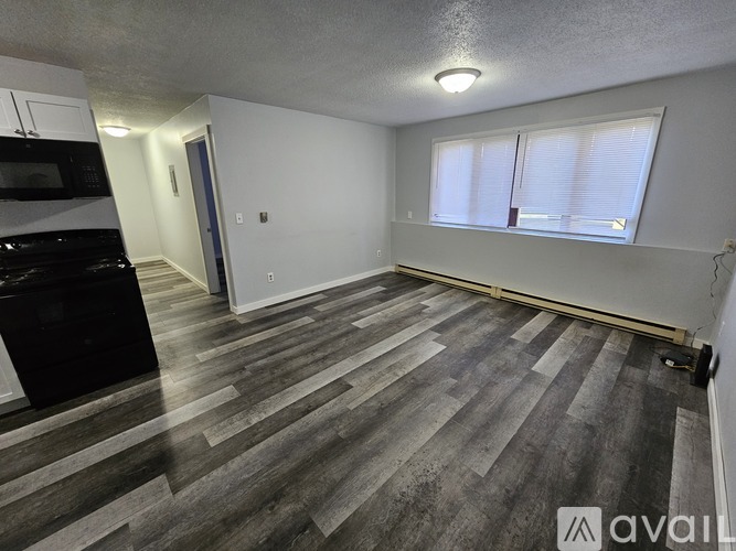 A room with wooden flooring and a window with blinds.