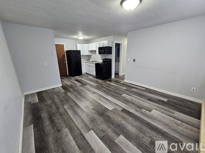 A kitchen area with a black refrigerator and white cabinets.