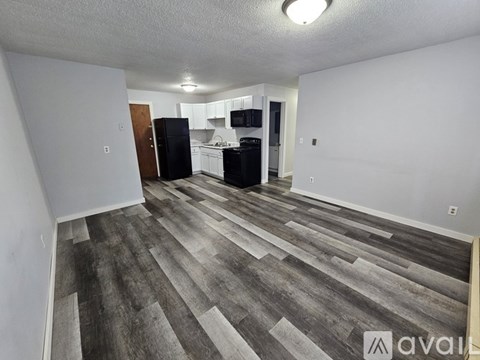 A kitchen area with a black refrigerator and white cabinets.
