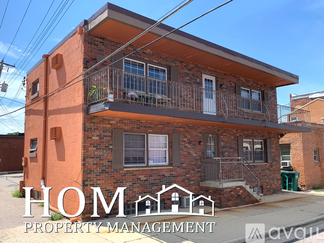A two-story brick house with a balcony on the second floor.