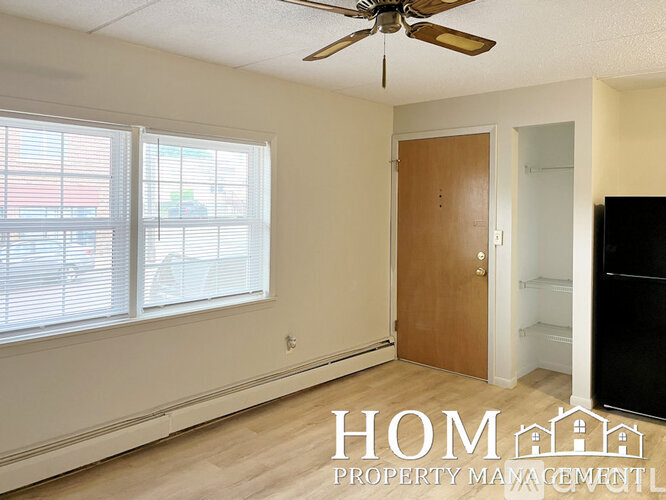 A room with a ceiling fan, a door, and a window with blinds.