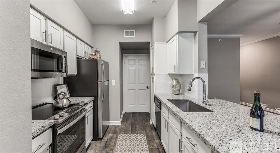A kitchen with a black fridge and white cabinets.
