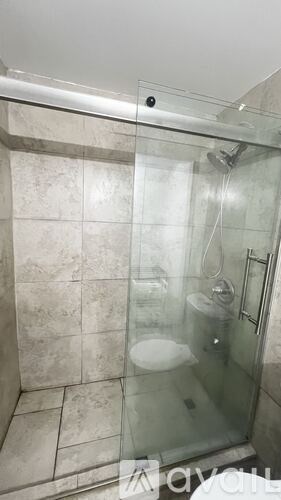 A shower area with a glass door and a white shower seat.