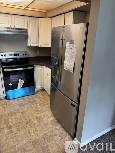 A kitchen with a stainless steel refrigerator and a stove with a blue box underneath it.
