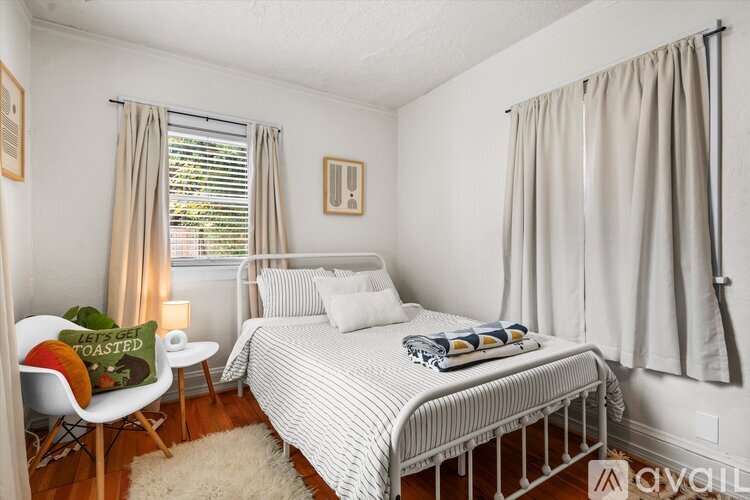 A bedroom with a bed, chair, and window.