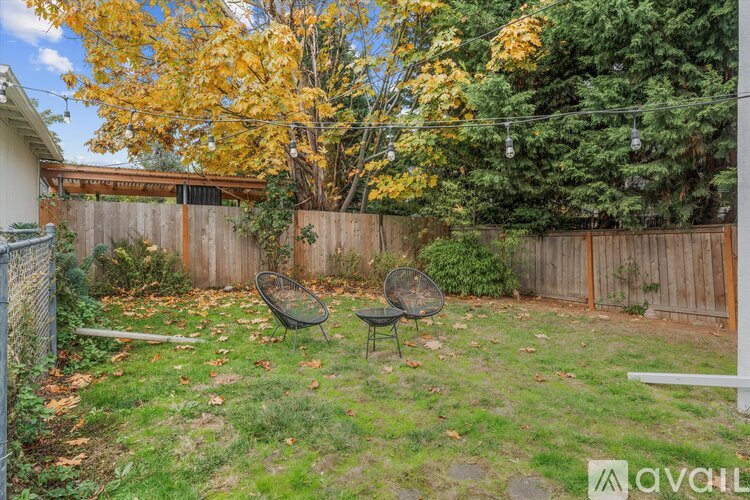A backyard with a fence, a swing set, and trees.