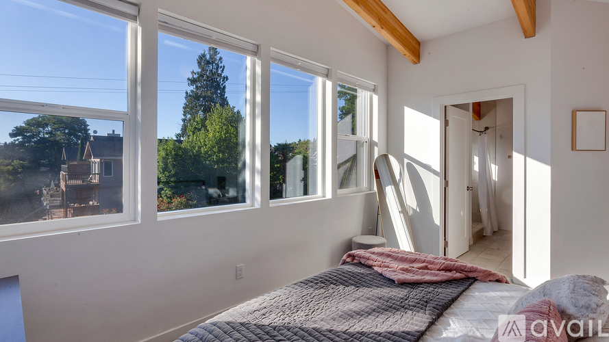 A bedroom with a large bed and a view of the backyard through the windows.