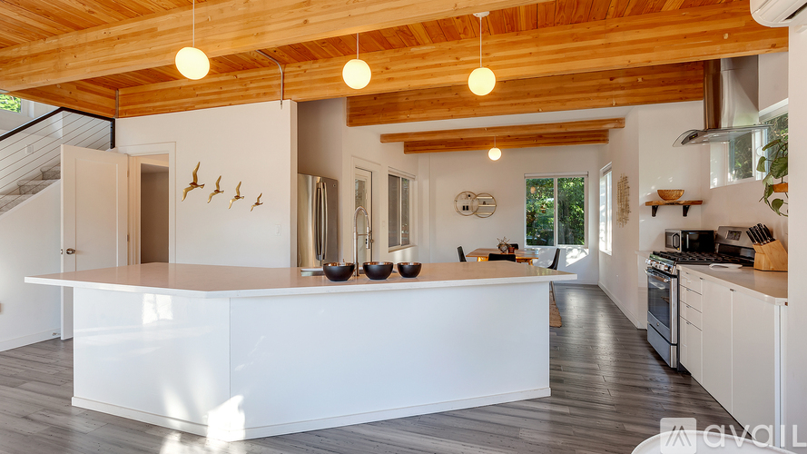 A kitchen with white cabinets and a wooden ceiling.