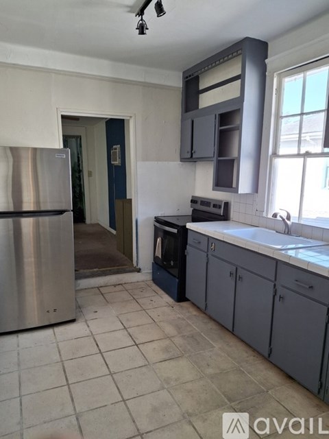 A kitchen with a stainless steel refrigerator and a window.