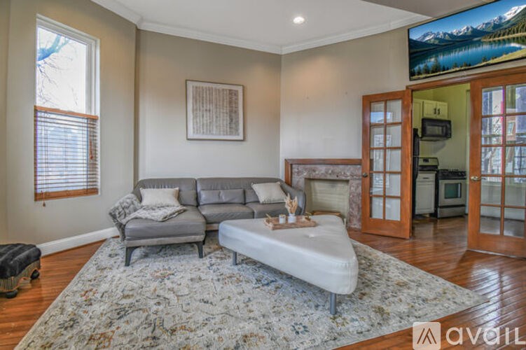 A living room with a grey couch and a rug.