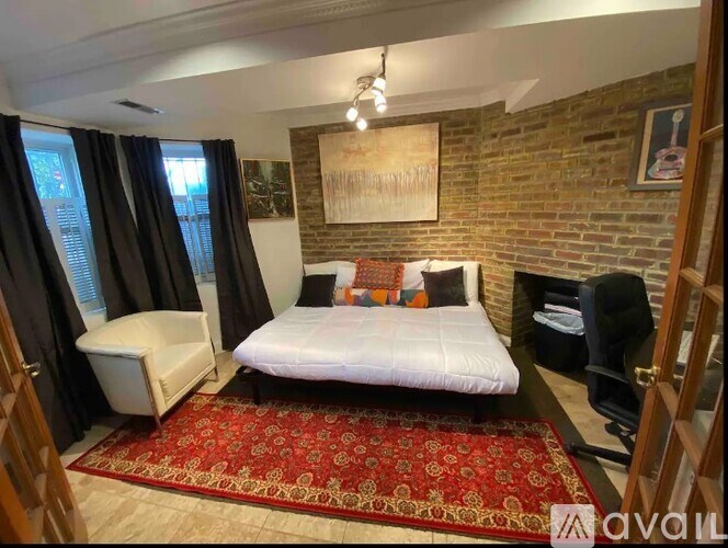 A bedroom with a brick wall and a red patterned rug.