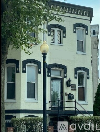A white building with black trim and a black lamp post in front.