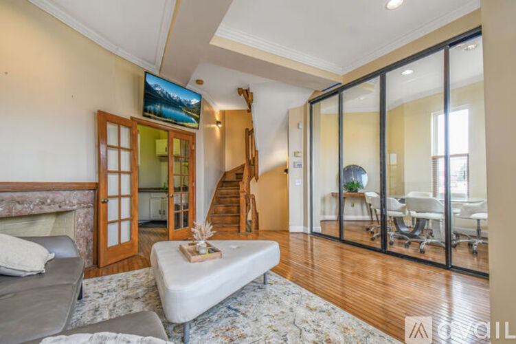 A living room with a grey couch and a flat screen TV mounted on the wall.