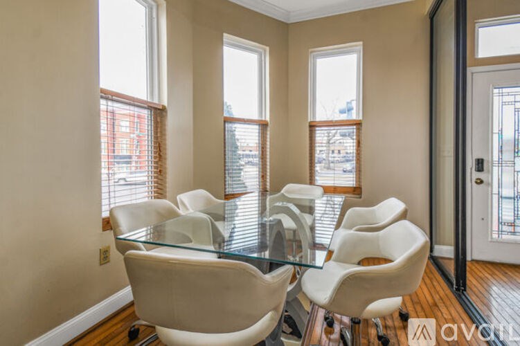 A conference room with a glass table and white chairs.