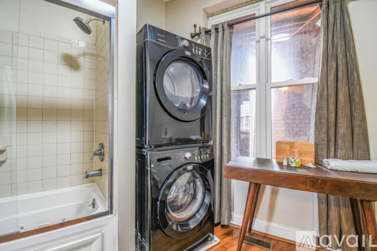 A black front loading washing machine in a small room.
