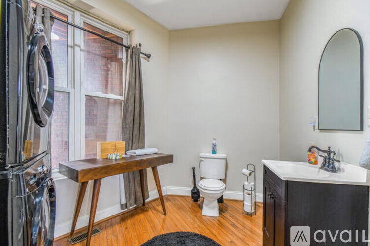 A bathroom with a toilet, sink, and a window.