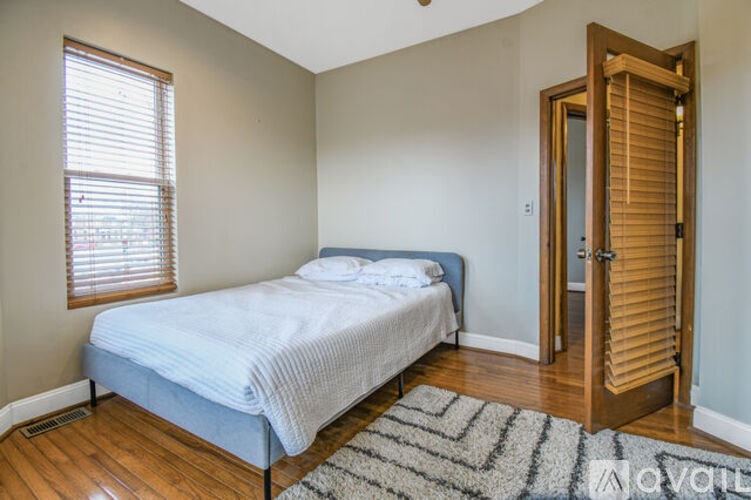 A bedroom with a bed, a rug, and a wooden door.