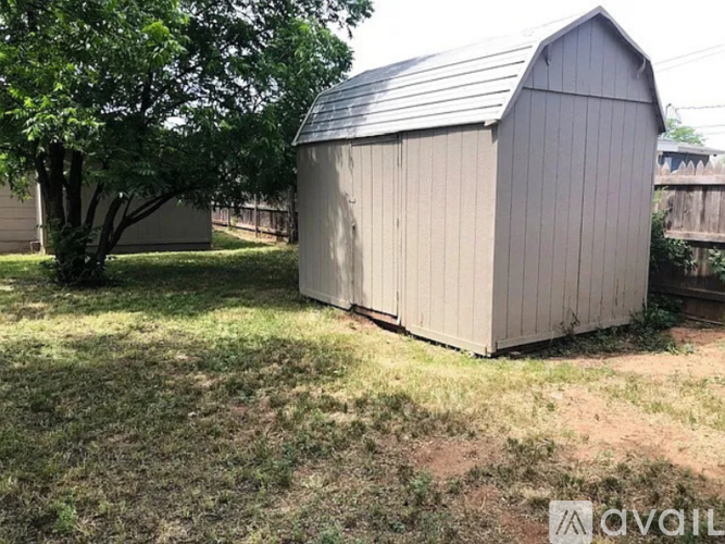 A grey shed sits in a grassy yard.