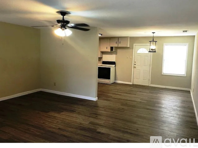 A room with a ceiling fan and wooden flooring.
