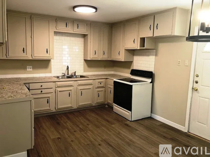 A kitchen with wooden floors and white cabinets.