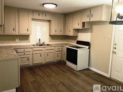 A kitchen with wooden floors and white cabinets.