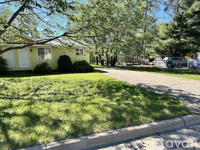 A house with a green lawn and trees in the background.