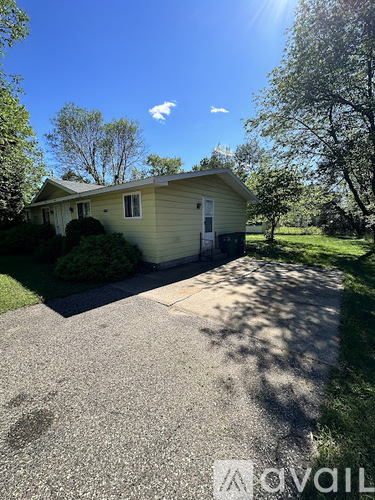 A house with a driveway and trees in the background.