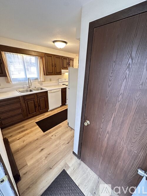 A kitchen with wooden floors and a brown door.