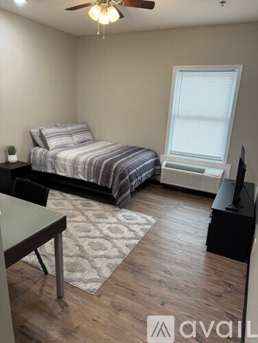 A bedroom with a bed, a window, and a ceiling fan.