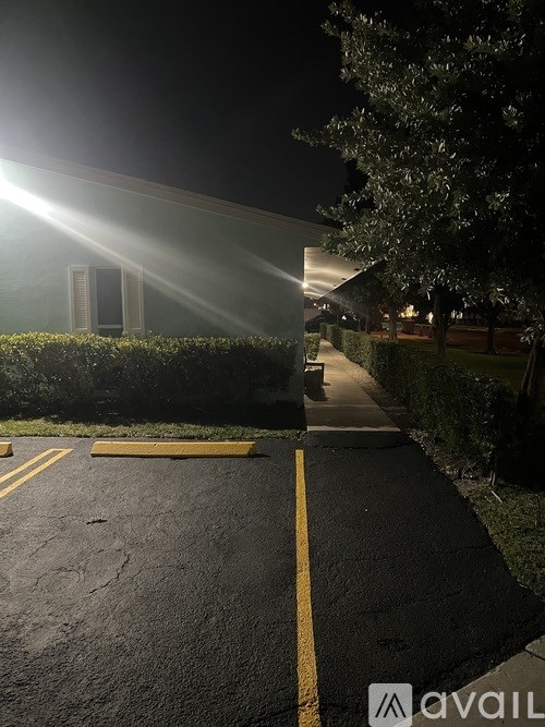 A parking lot at night with a building in the background.