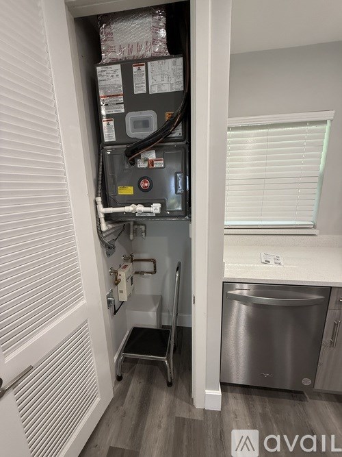 A small kitchen with a stainless steel dishwasher and a refrigerator with many papers attached to it.