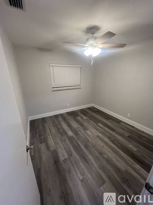 A room with a ceiling fan and wooden flooring.