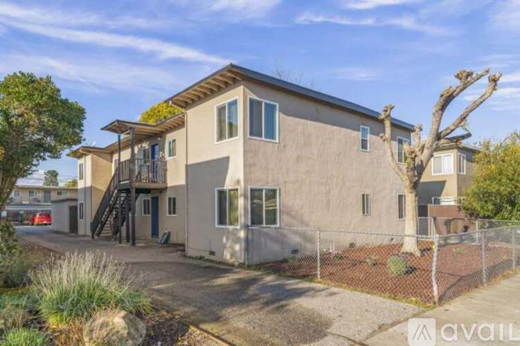 A house with a fence and a tree in front of it.