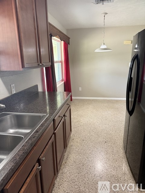 A kitchen with brown cabinets and a black fridge.