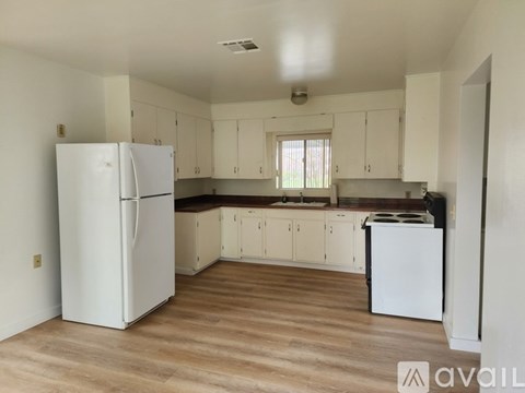 A kitchen with white appliances and wooden floors.
