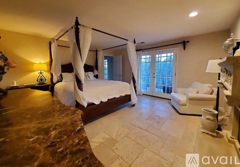A bedroom with a large bed and a window with curtains.