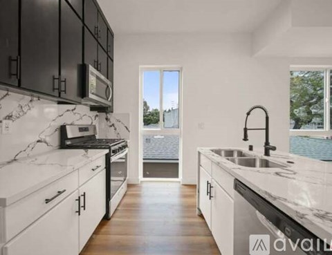 A modern kitchen with black cabinets and white marble countertops.