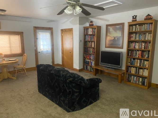 A living room with a black couch, a television, and a bookshelf.