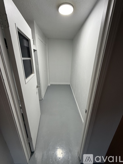 A long, narrow hallway with a door on the left and a window on the right.