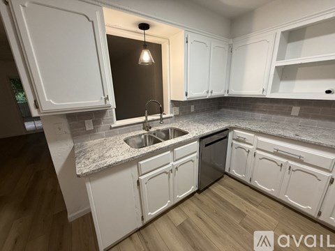 A kitchen with white cabinets and a granite countertop.
