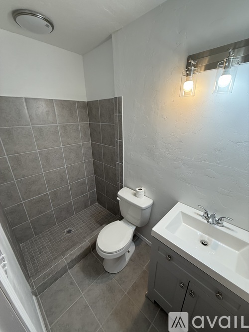 A bathroom with a toilet, sink, and tiled shower.