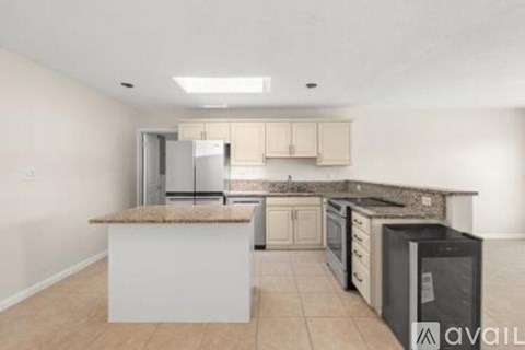 A kitchen with a white island and a black fridge.
