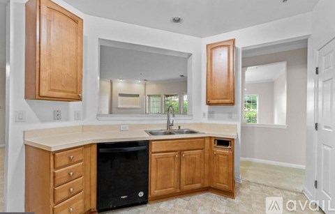 A kitchen with wooden cabinets and a black dishwasher.
