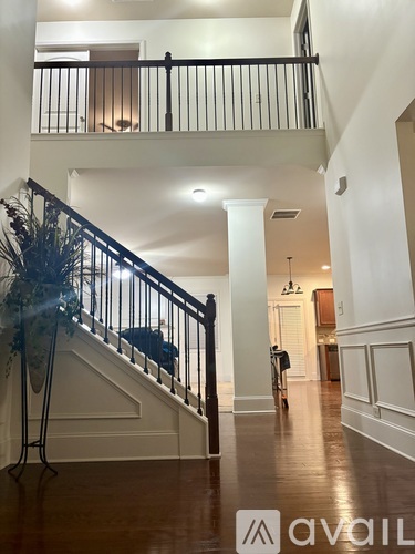 A hallway with a staircase and a person walking in the distance.