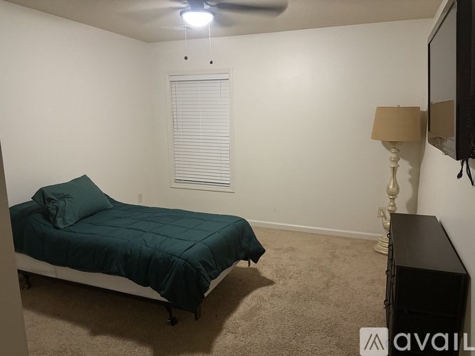 A bedroom with a bed, a lamp, and a television.
