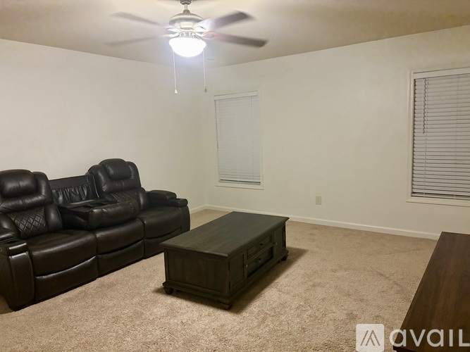 A living room with a black leather couch and a wooden coffee table.