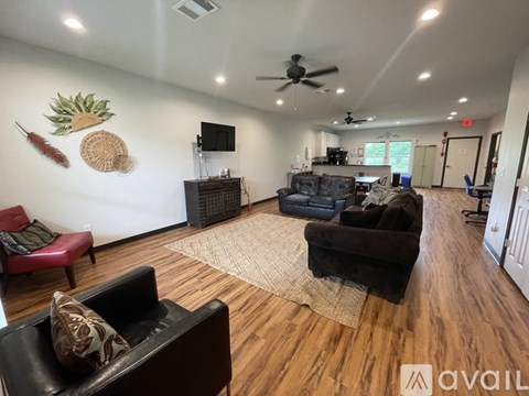 A living room with a black couch and a wooden floor.
