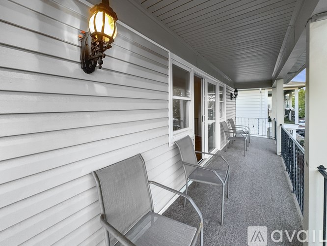 A porch with a light on the wall and chairs.