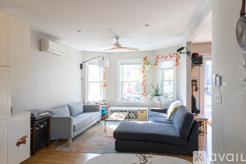 A living room with a grey couch and a rug.