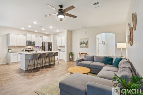 A living room with a grey couch and a bar area with stools.
